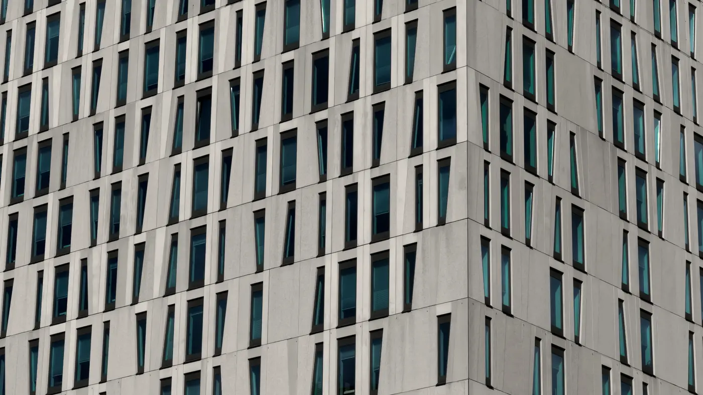 White high-rise facade with rows of angled narrow windows