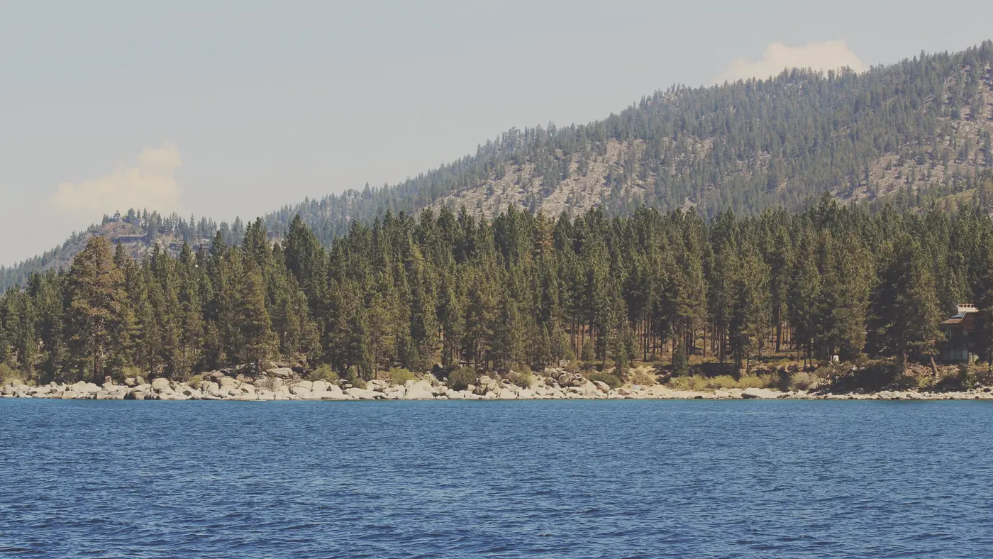 Calm blue lake below a forested mountain ridge