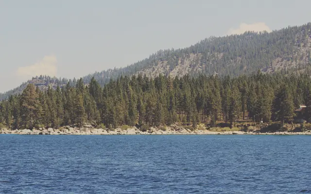 Calm blue lake below a forested mountain ridge