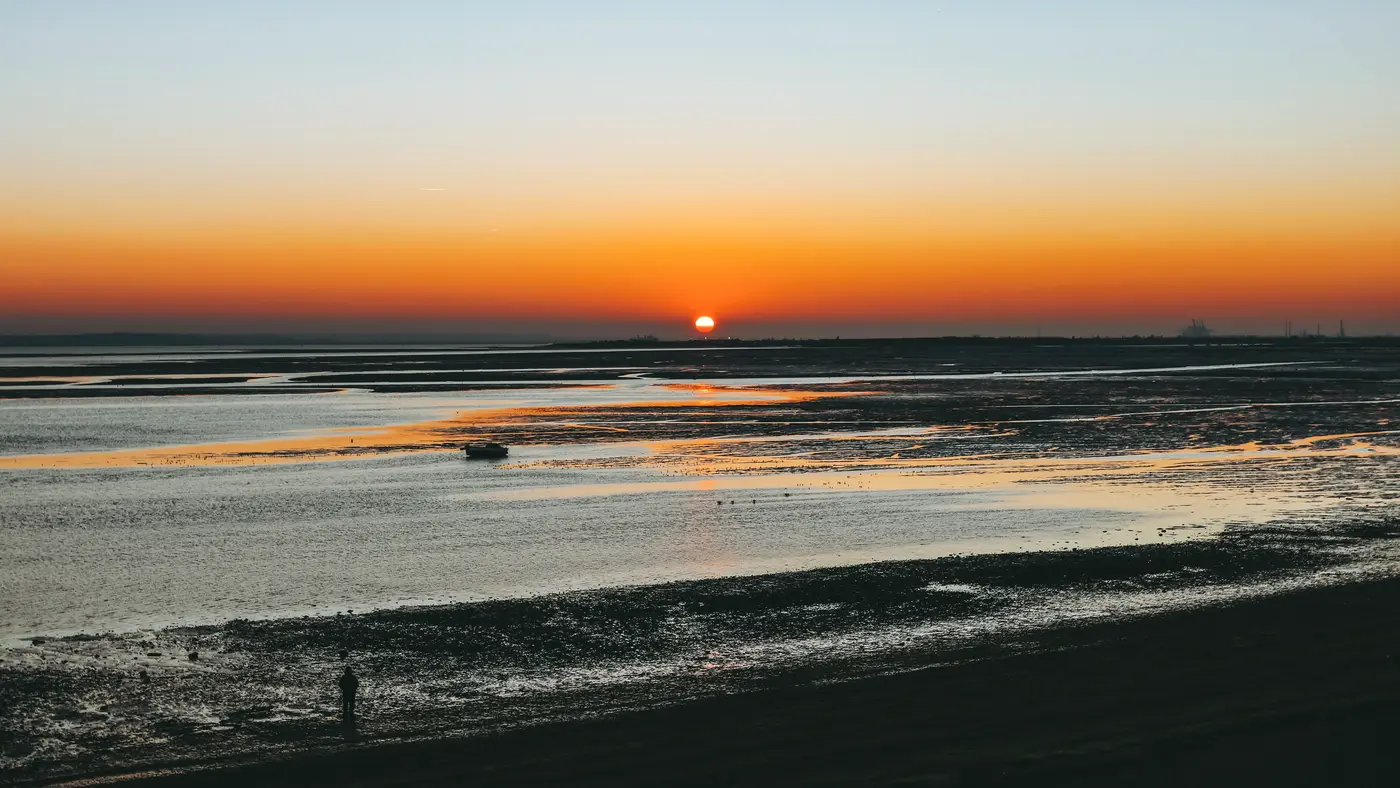 Calm tidal beach with the sun setting on the horizon