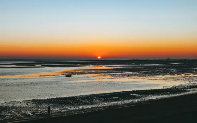 Calm tidal beach with the sun setting on the horizon