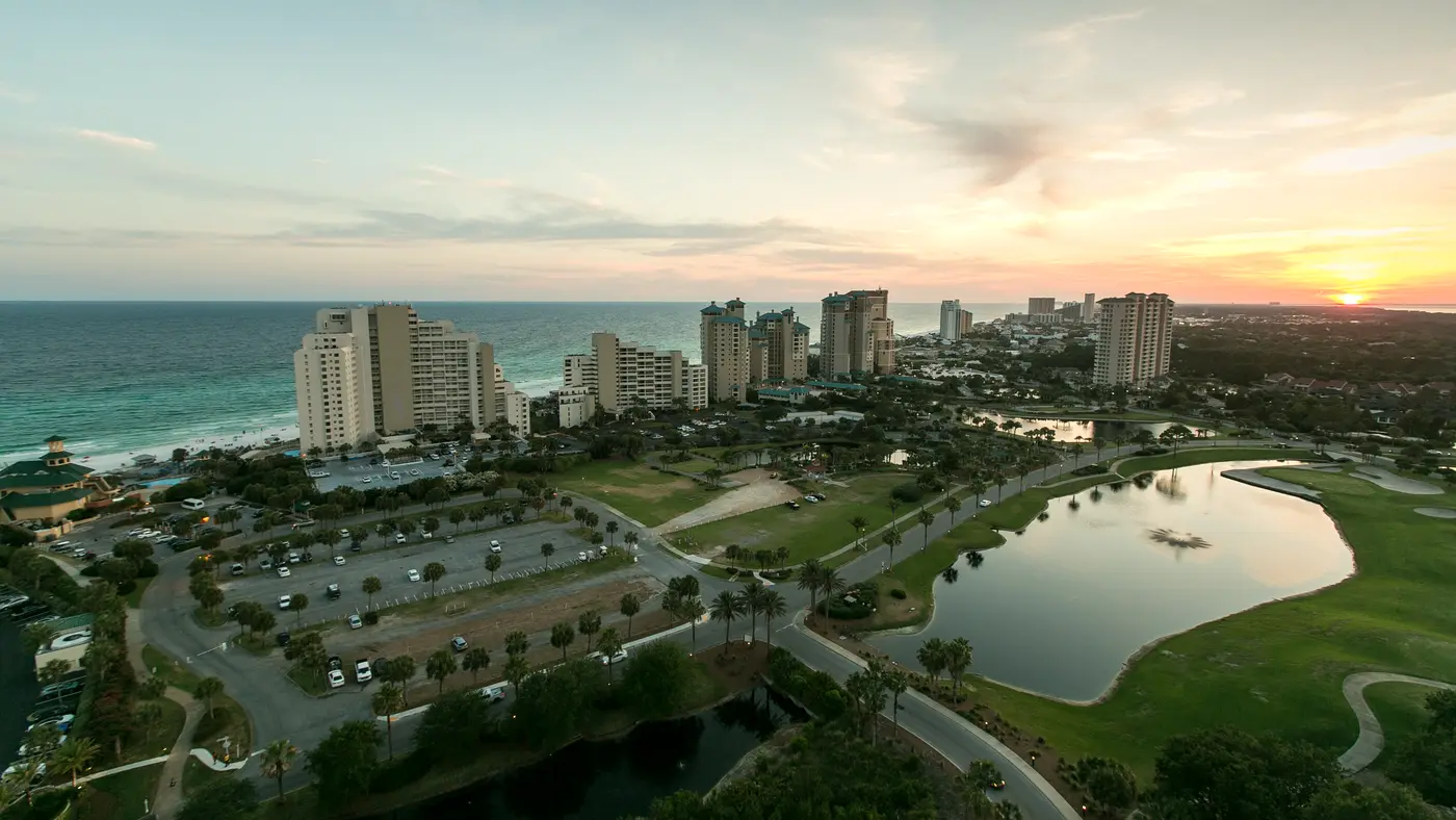 Coastal golf course and pond beside beachfront towers at sunset