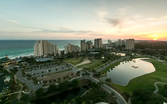 Coastal golf course and pond beside beachfront towers at sunset