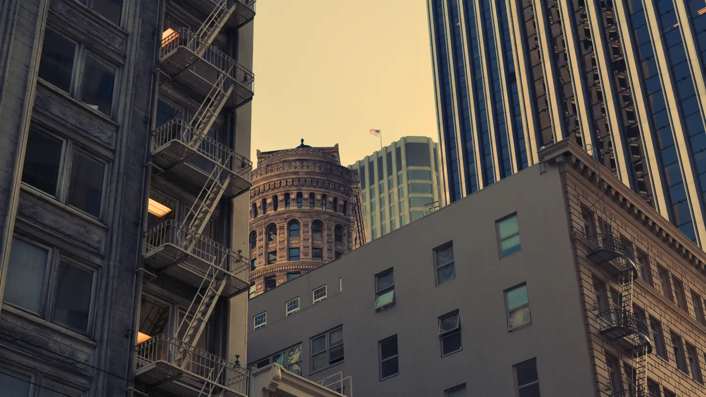 Older downtown buildings with fire escapes beside modern towers