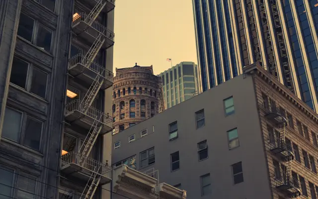 Older downtown buildings with fire escapes beside modern towers