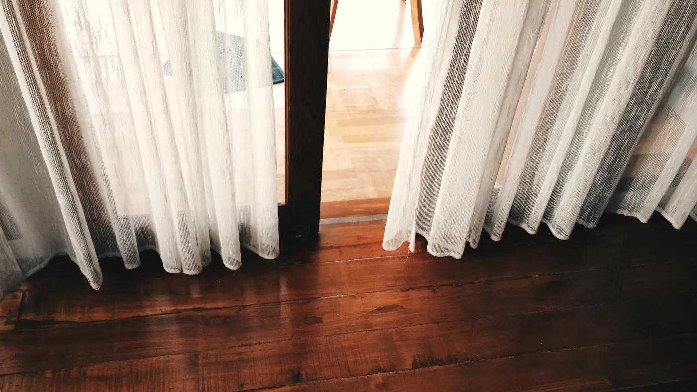 Sheer curtains drawn over a doorway in a quiet empty room