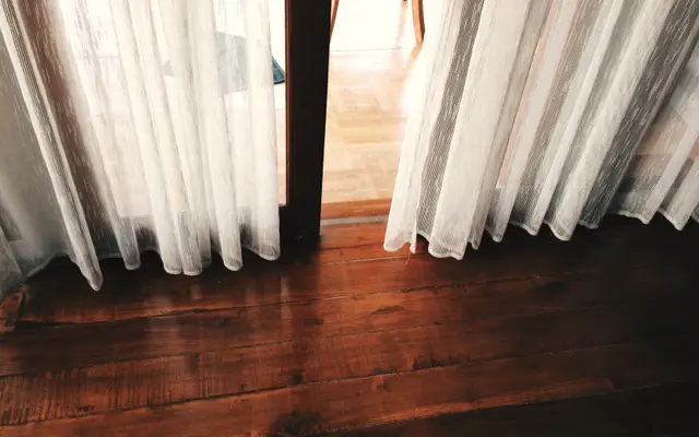 Sheer curtains drawn over a doorway in a quiet empty room