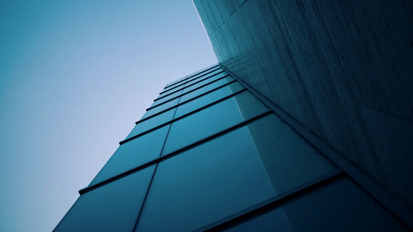 Corner of a dark blue glass building against clear sky