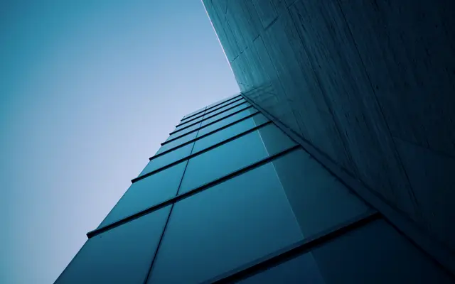 Corner of a dark blue glass building against clear sky