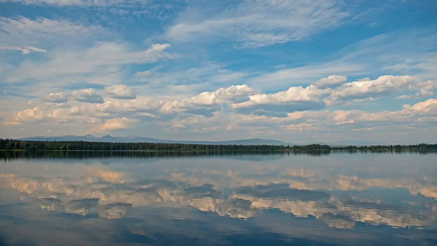 Still lake reflecting a wide sky of scattered clouds
