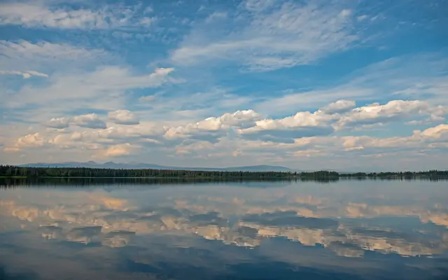 Still lake reflecting a wide sky of scattered clouds