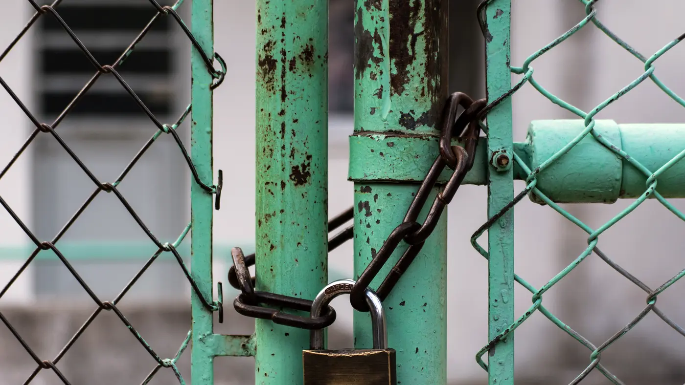 Padlock and chain securing a green chain-link gate