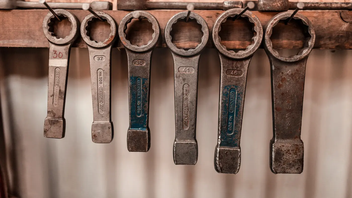Row of heavy ring spanners hanging on a workshop wall