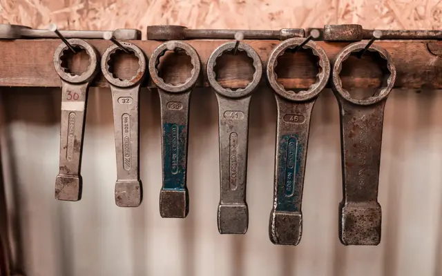 Row of heavy ring spanners hanging on a workshop wall