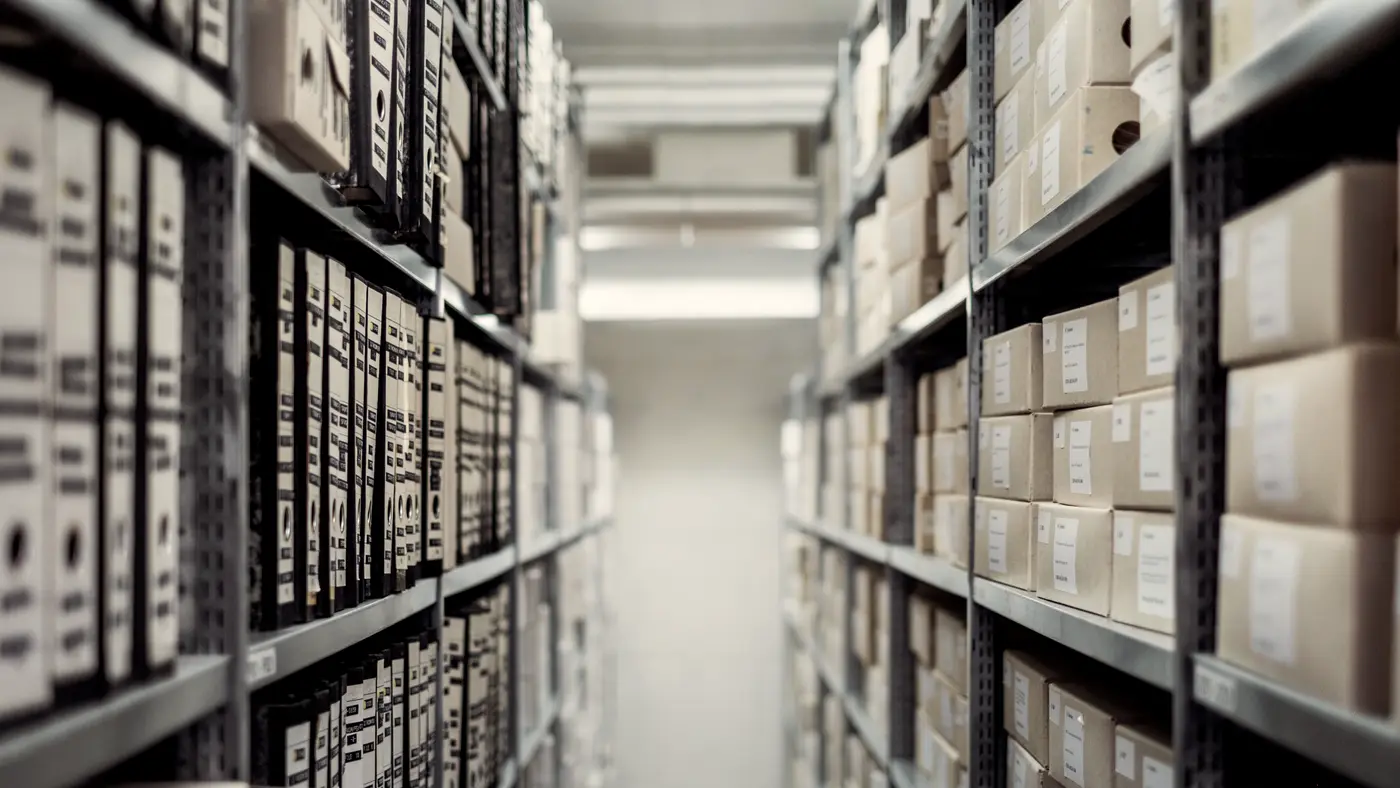 Narrow aisle between tall steel shelves stacked with storage boxes