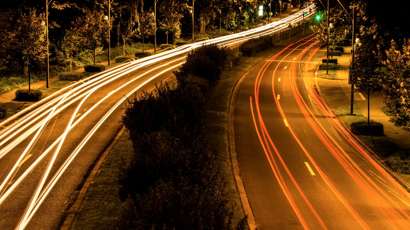 Curving highway at night with streaks of car light trails