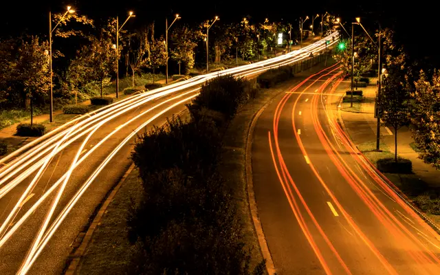 Curving highway at night with streaks of car light trails