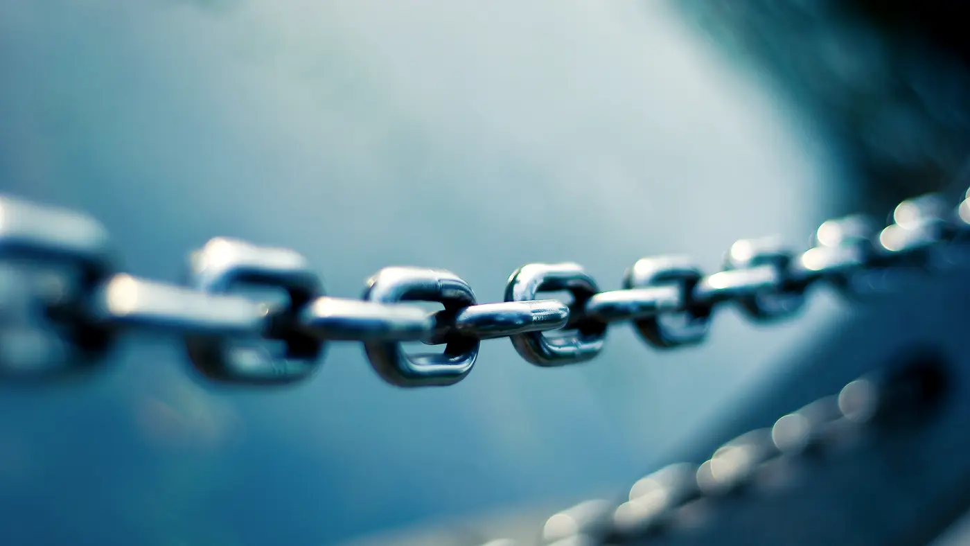 Close-up of a heavy steel chain against a blue background