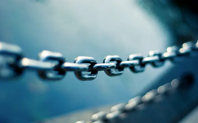 Close-up of a heavy steel chain against a blue background