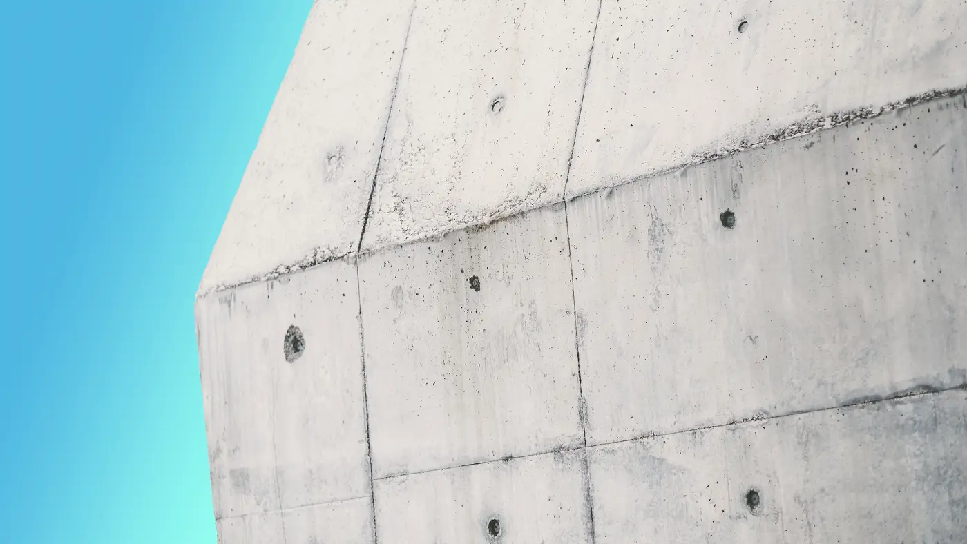 Board-formed concrete building corner against a clear blue sky