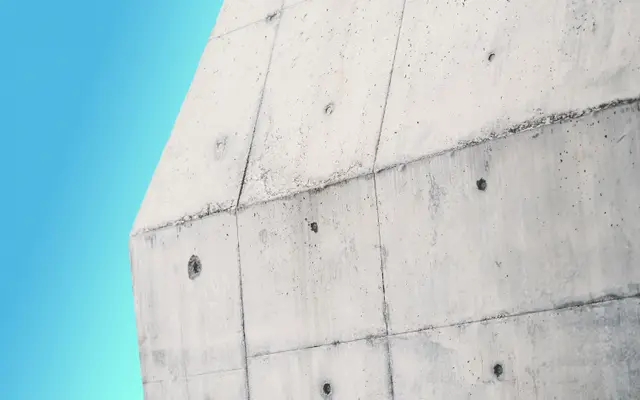 Board-formed concrete building corner against a clear blue sky
