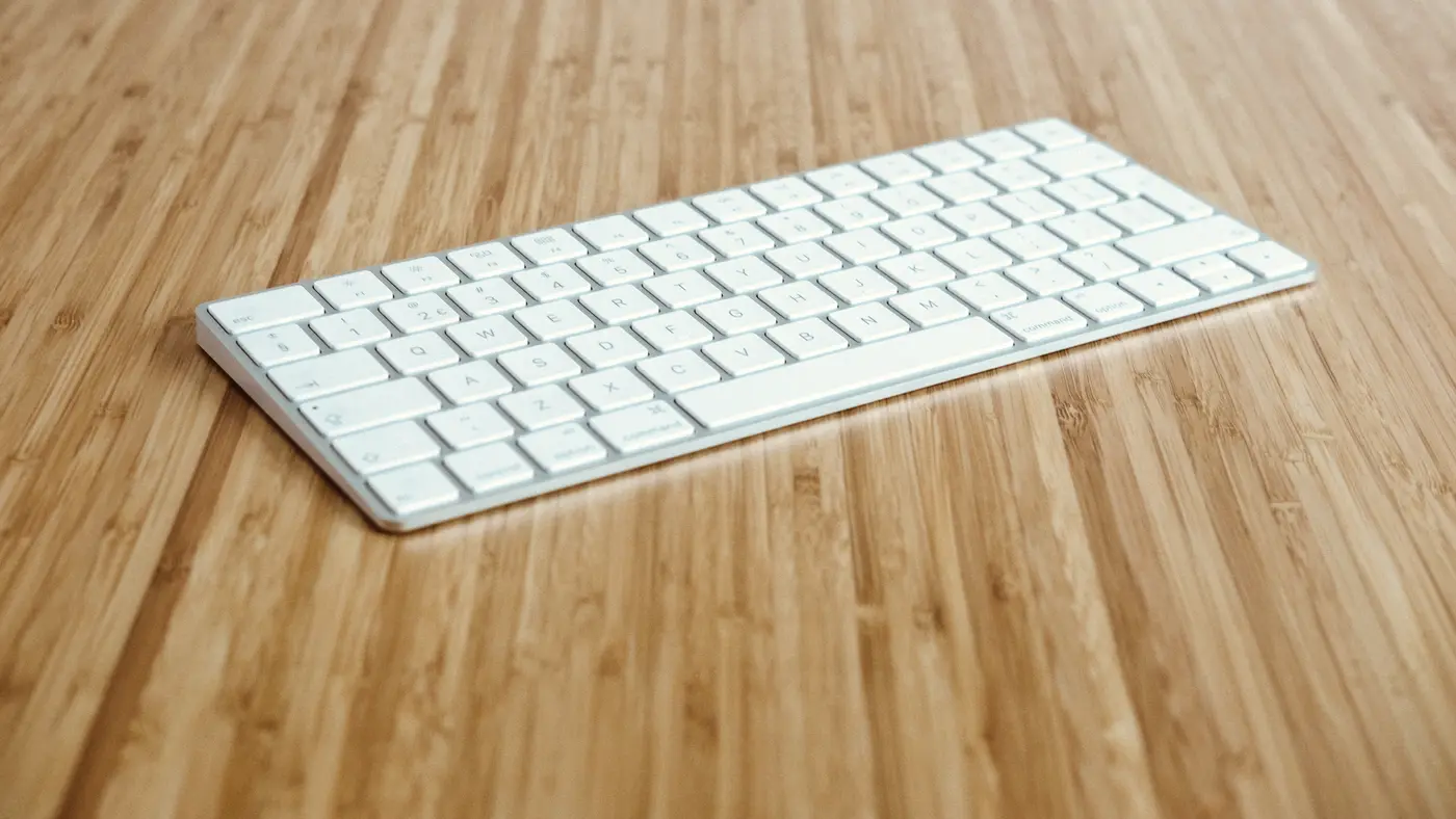 White wireless keyboard on a light bamboo desk