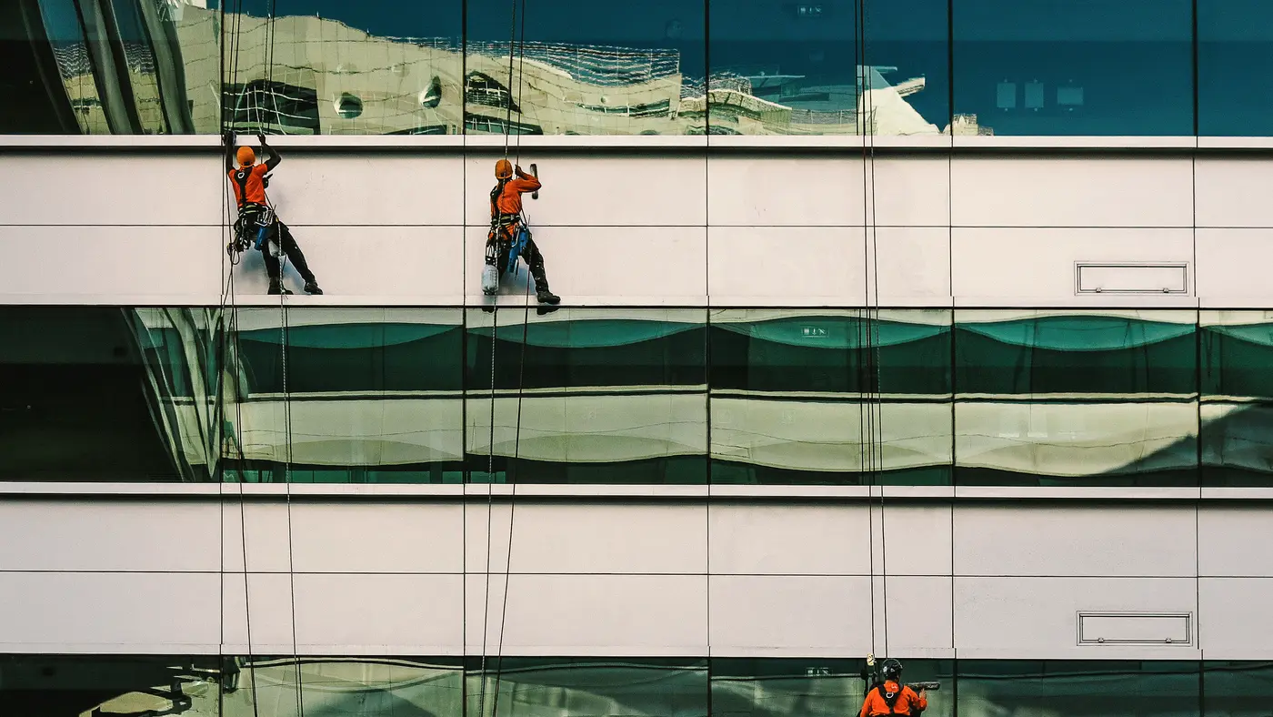 Rope access workers cleaning windows on a modern office building