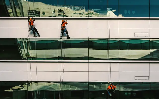 Rope access workers cleaning windows on a modern office building