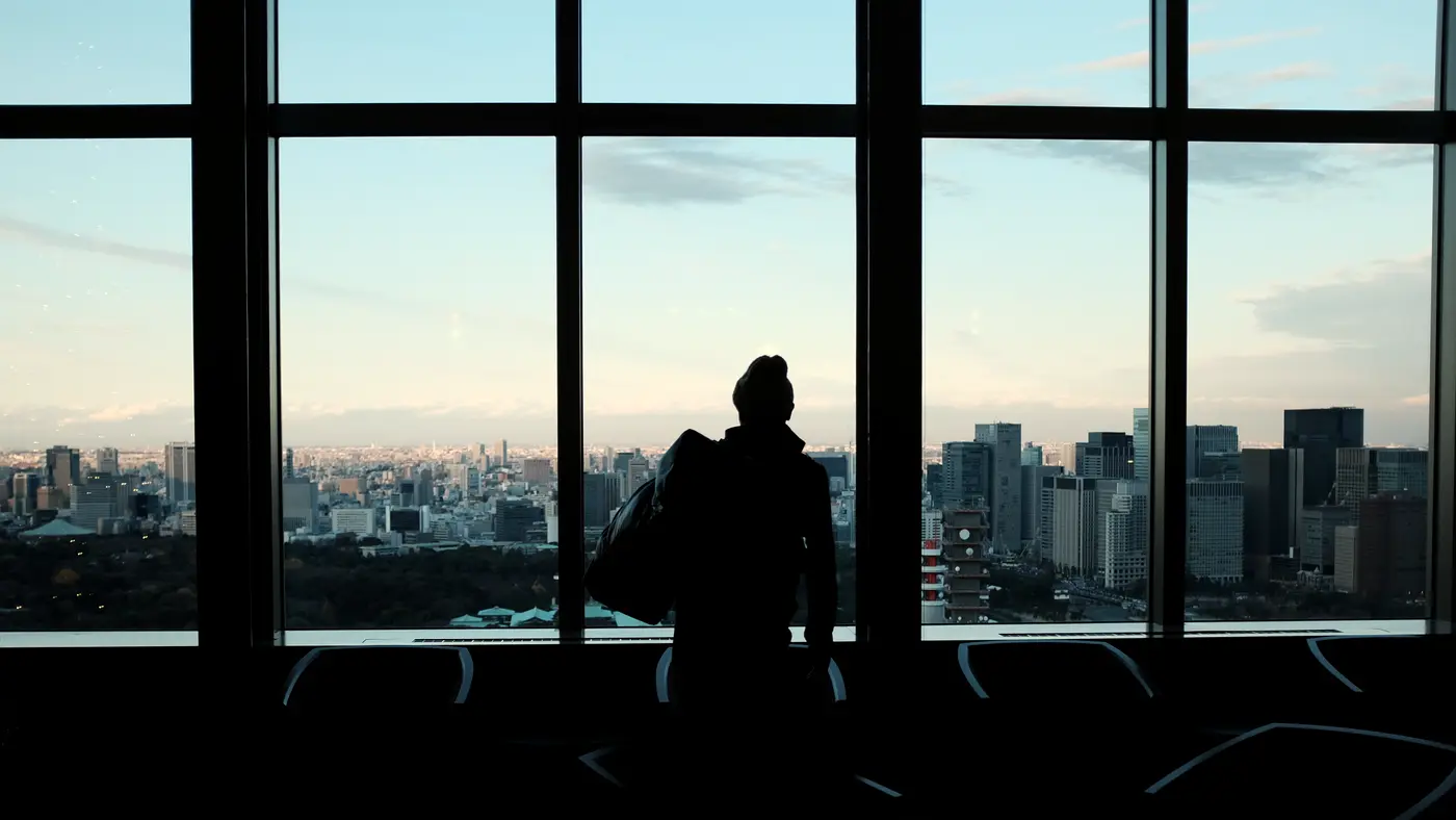 Silhouette of a person at an office window above a city skyline