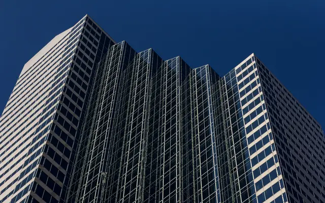 Glass office skyscraper against a deep blue sky