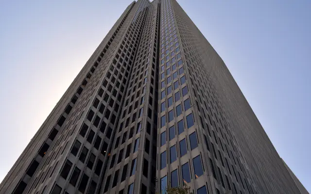 Glass and steel skyscraper seen from below against a blue sky