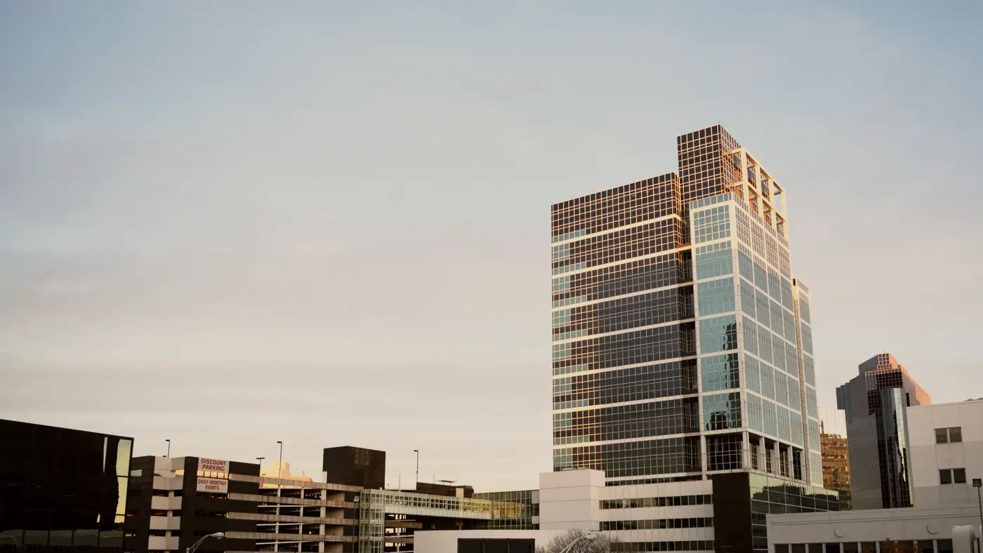 Glass office building rising above a low city skyline
