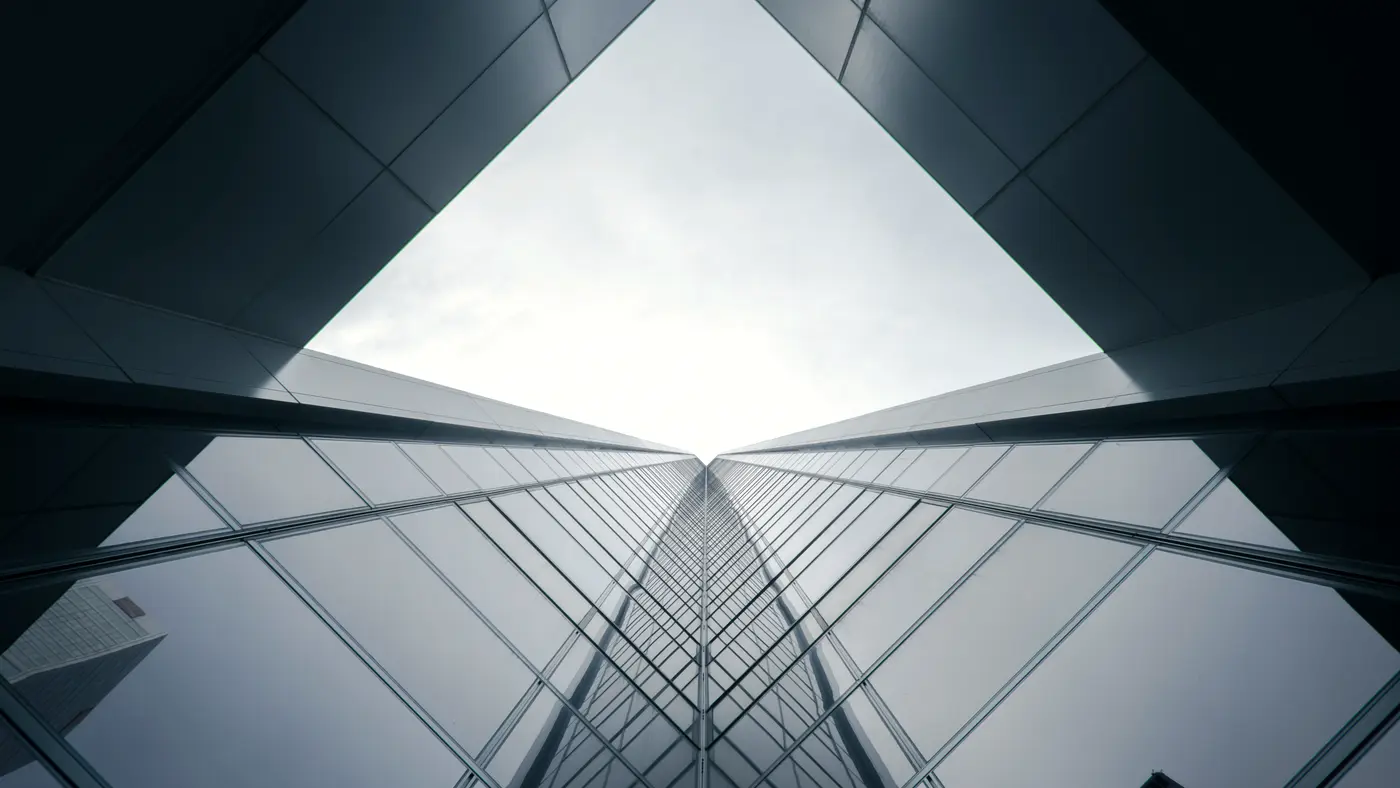 Glass office towers converging overhead against a pale grey sky