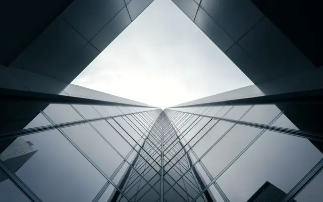 Glass office towers converging overhead against a pale grey sky