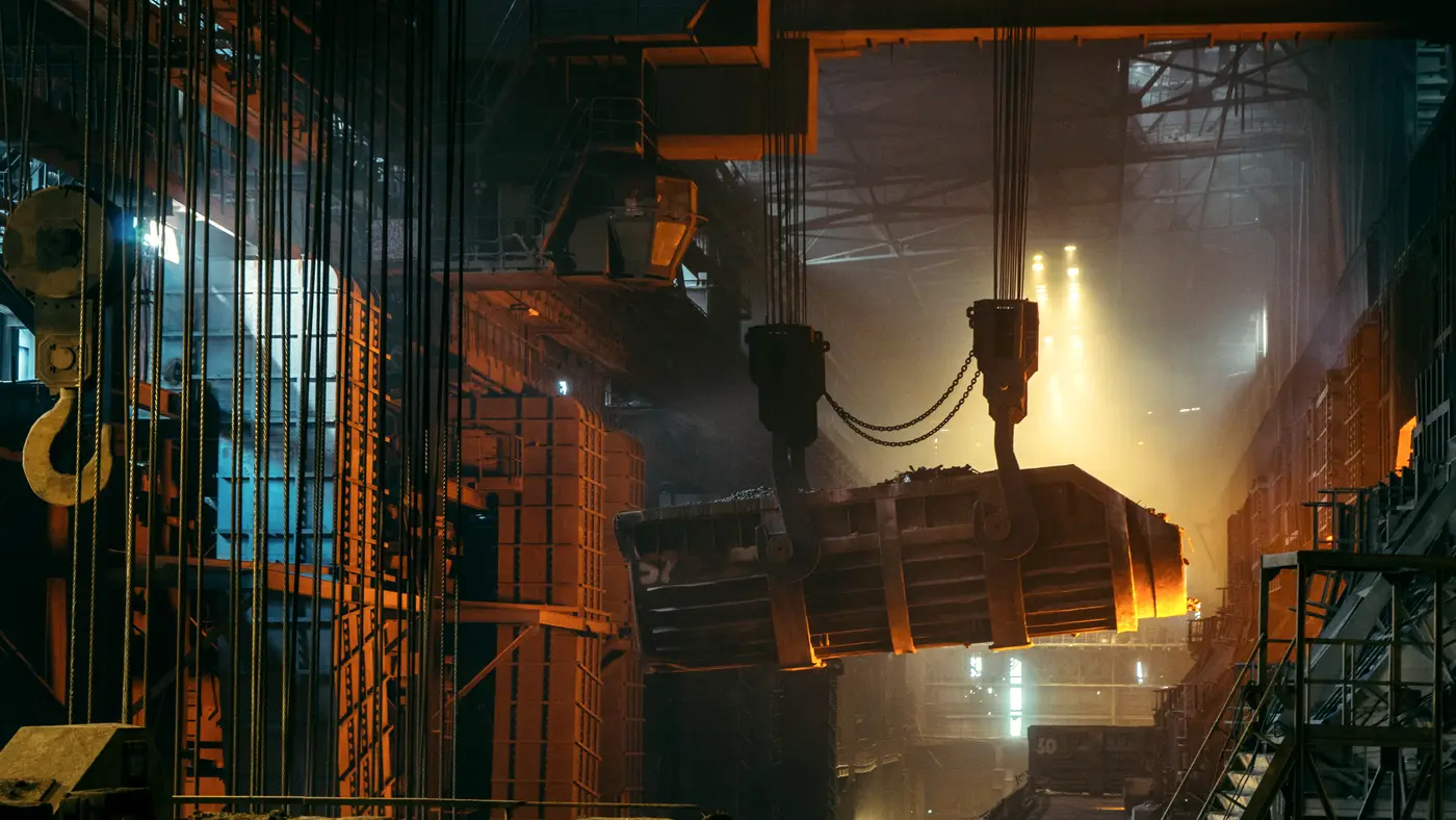 Crane lifting a molten metal ladle inside a steel mill