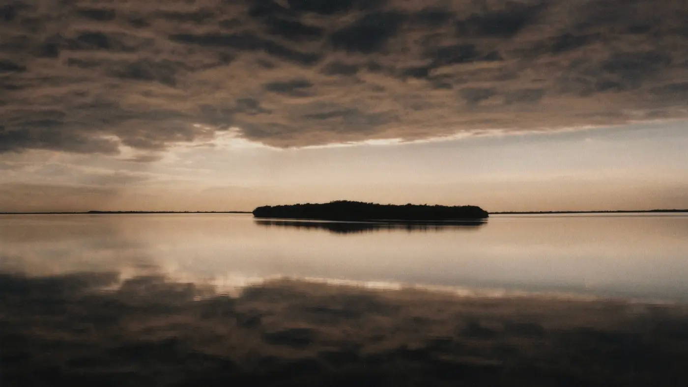 Calm lake with a small island reflecting a cloudy dusk sky