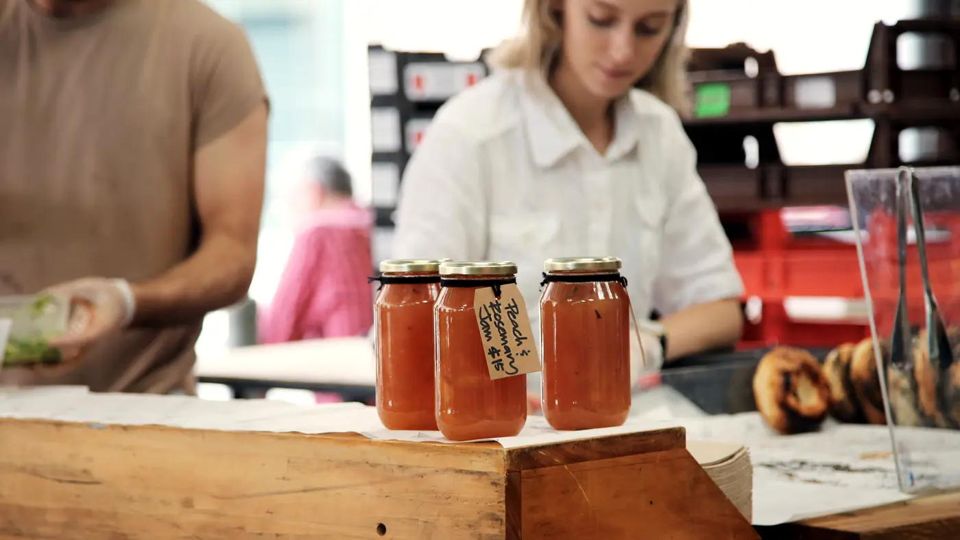 Market stall vendor arranging jars of homemade preserves