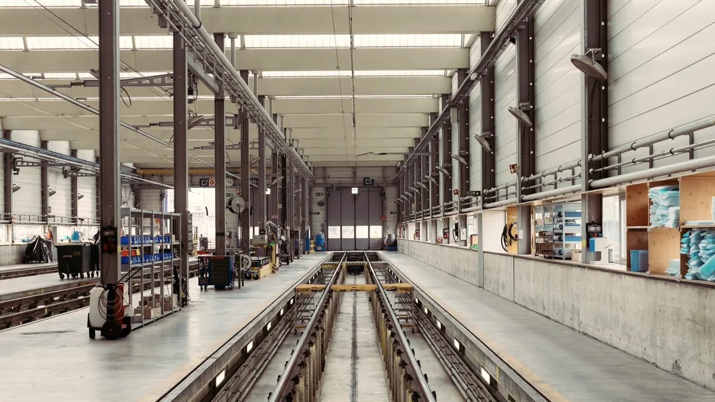 Long clean factory hall with rails and workstations