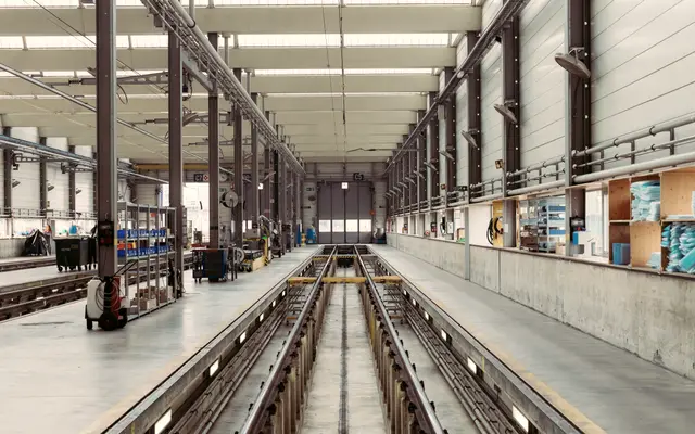 Long clean factory hall with rails and workstations