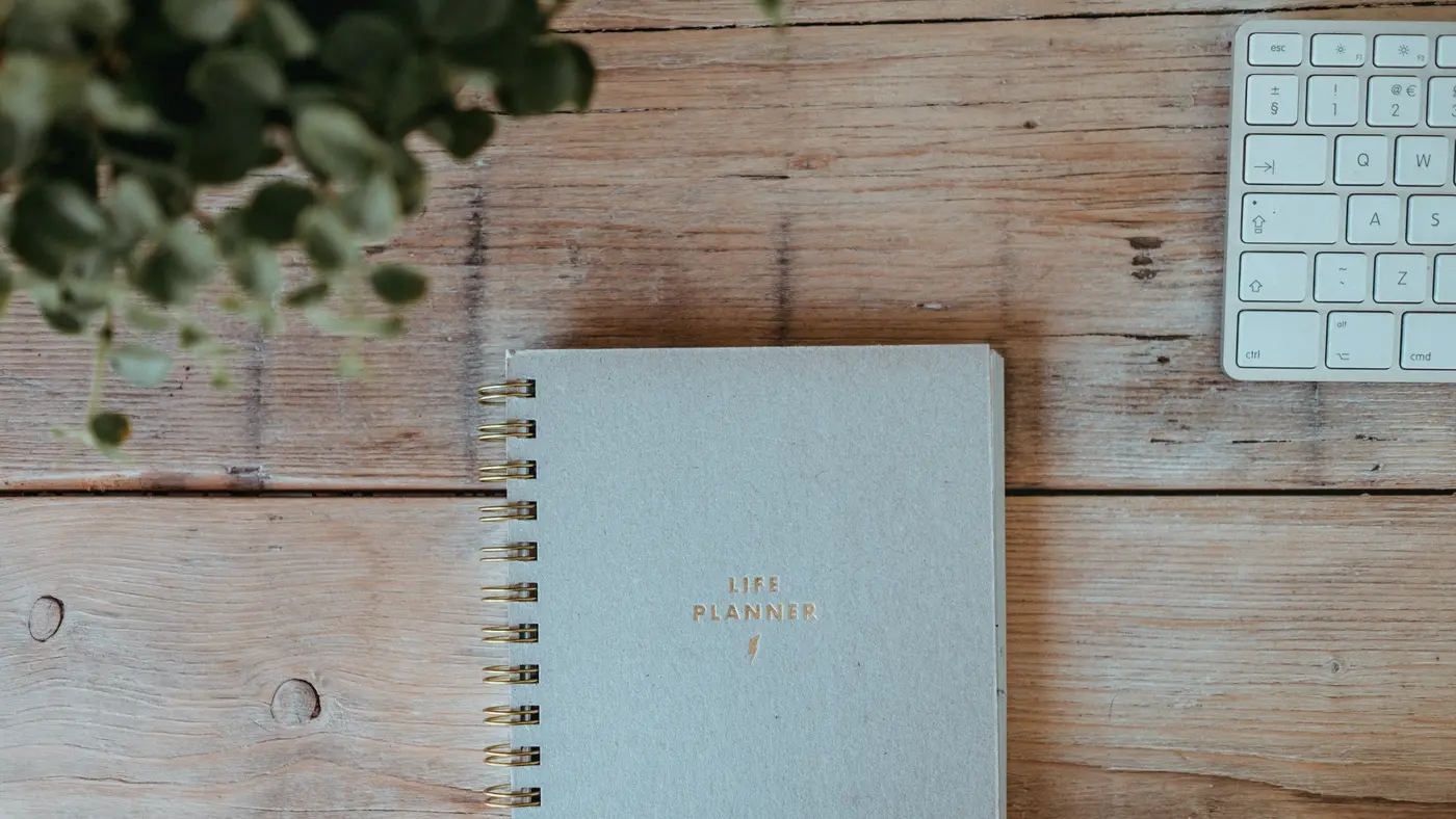 Notebook beside a keyboard on a light wooden desk