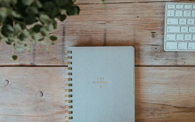 Notebook beside a keyboard on a light wooden desk
