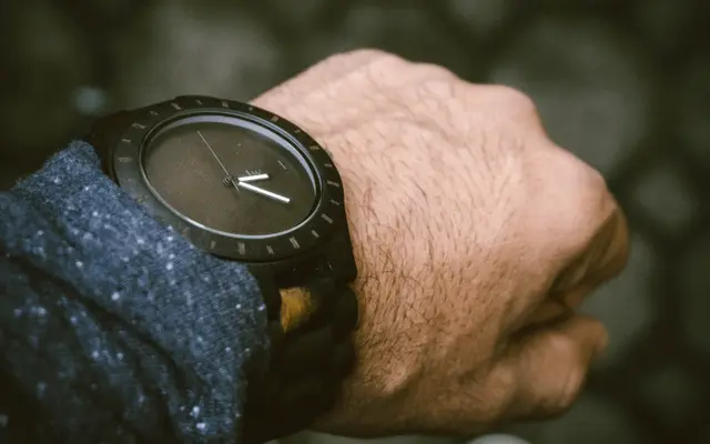 Close-up of a dark wooden wristwatch on a man's wrist