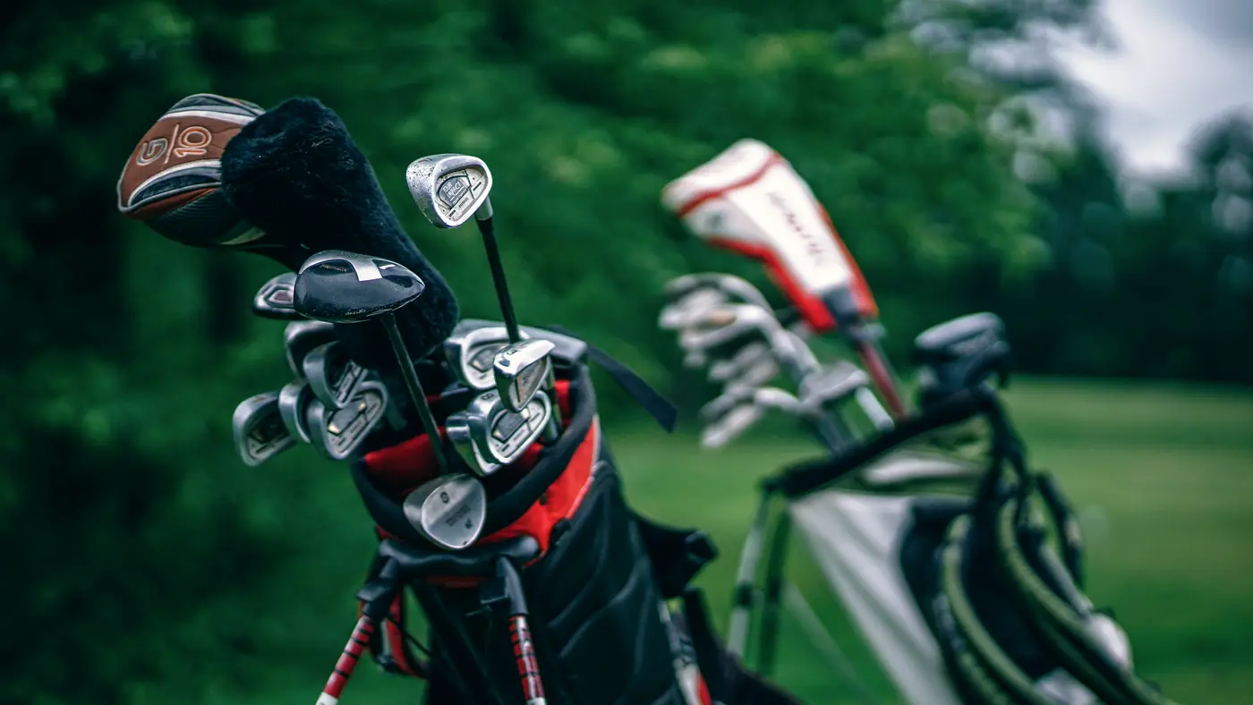 Golf bags full of clubs resting on a green course