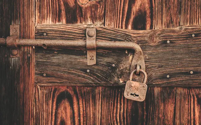 Old padlock on an iron latch of a weathered wooden door