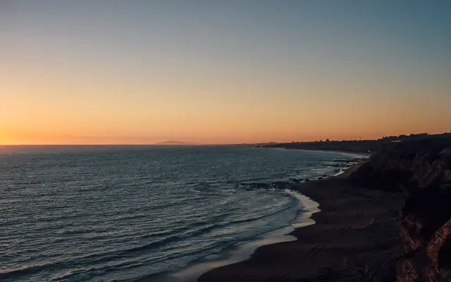 Quiet coastline and bluffs at dusk under a clear orange sky