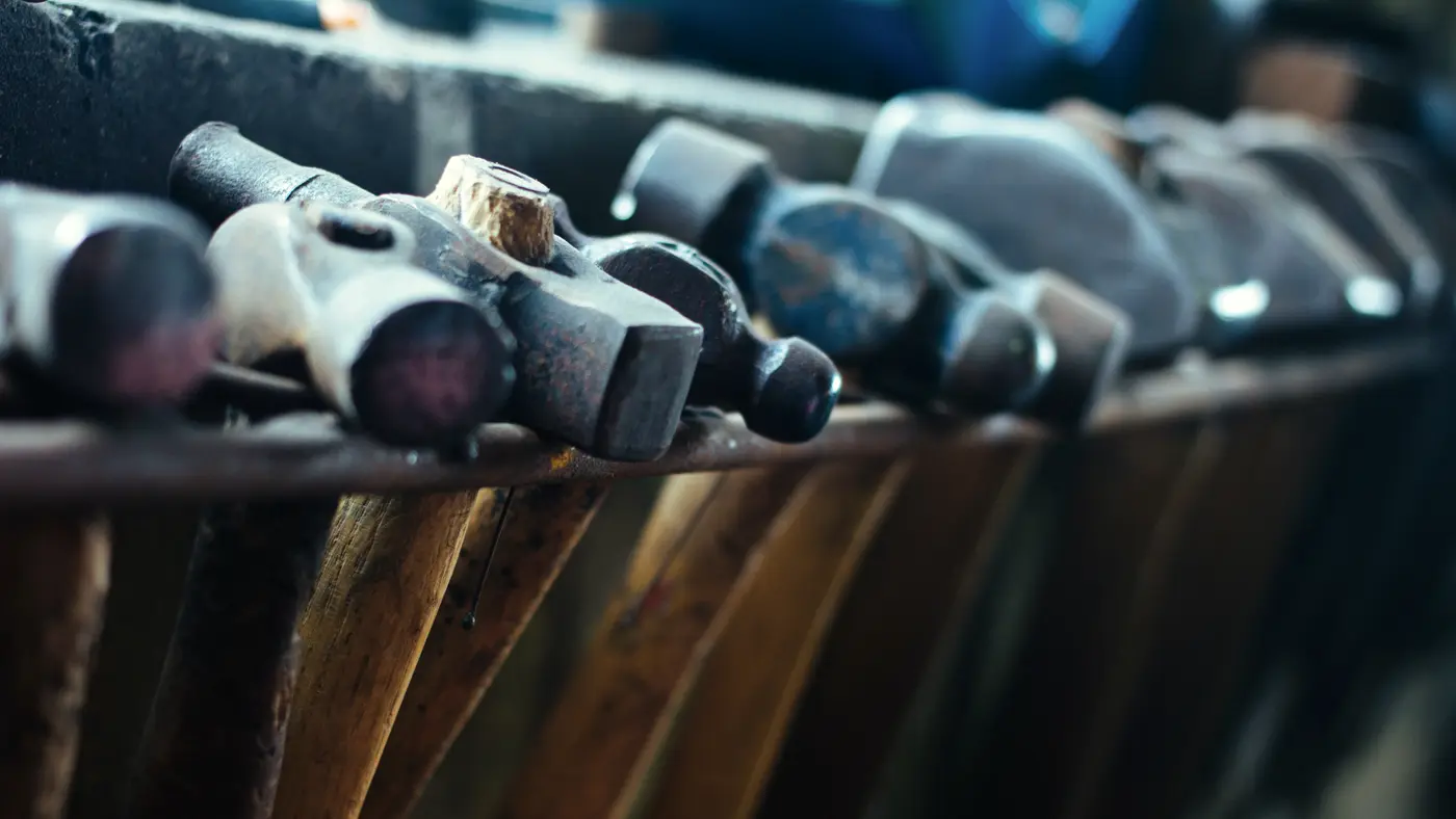 Row of worn hammers resting in a wooden rack