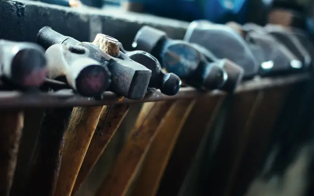 Row of worn hammers resting in a wooden rack