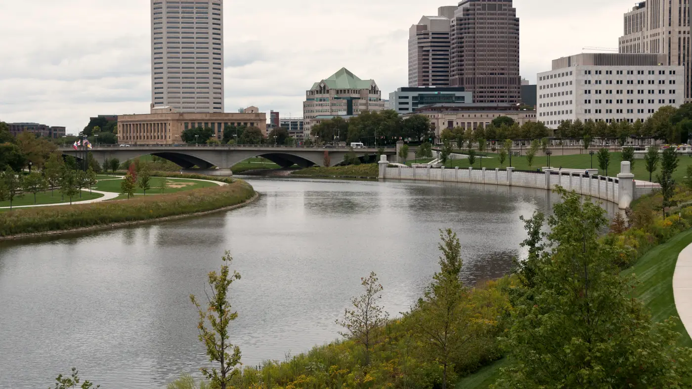 Downtown skyline above a riverside park and green riverbank