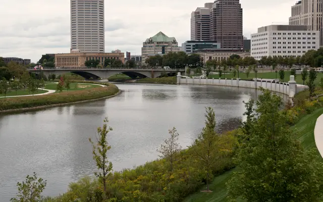 Downtown skyline above a riverside park and green riverbank