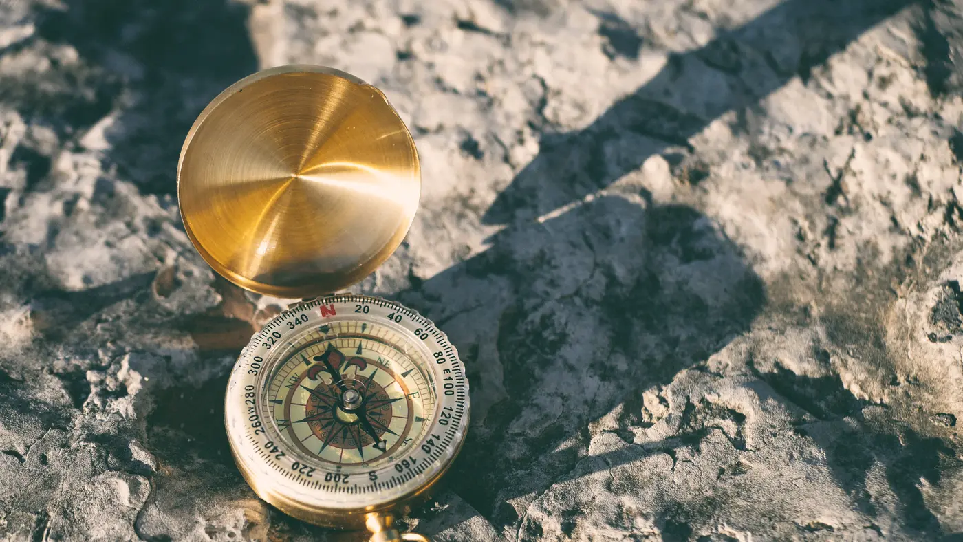 Brass compass lying open on a sunlit rocky surface